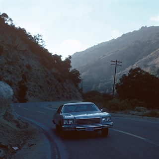 Old 1970s car driving through mountains