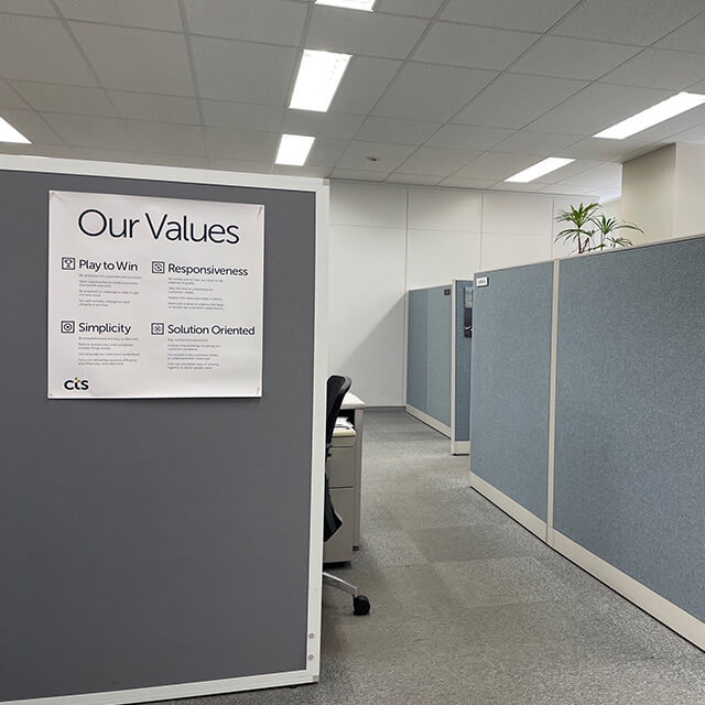 Inside CTS office with cubical walls and sign that lists CTS' "Our Values proposition located in Japan