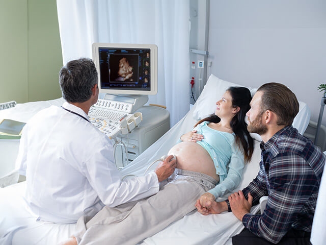 Ultrasound technician and woman looking at screen of 3D fetus