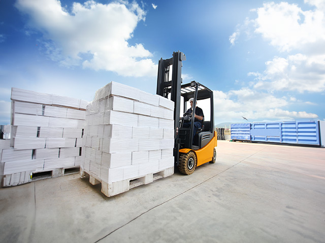 Man using forklift moving heavy blocks on palate